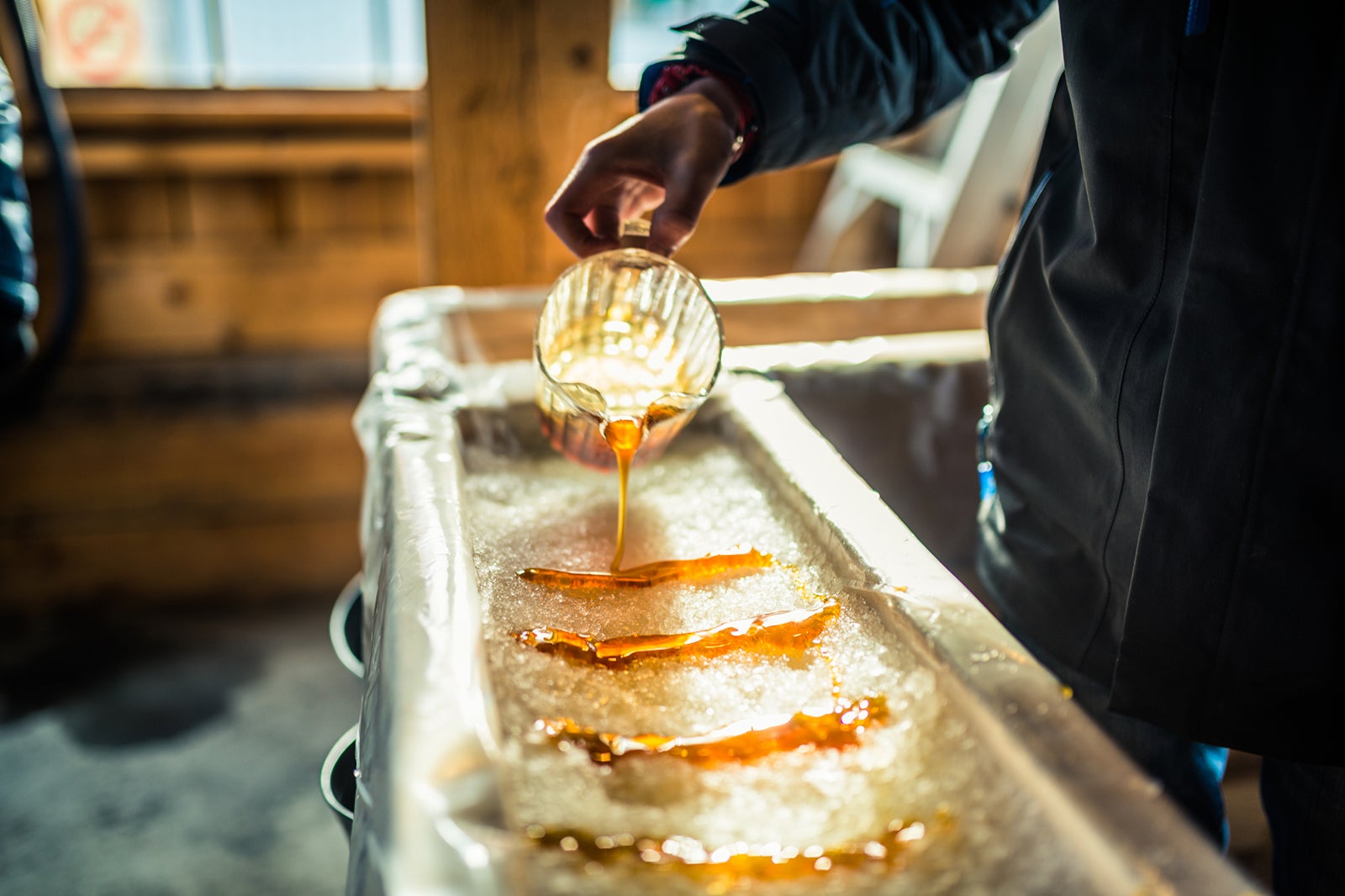 Person pouring maple syrup onto snow at sugar shack Quebec Warchi