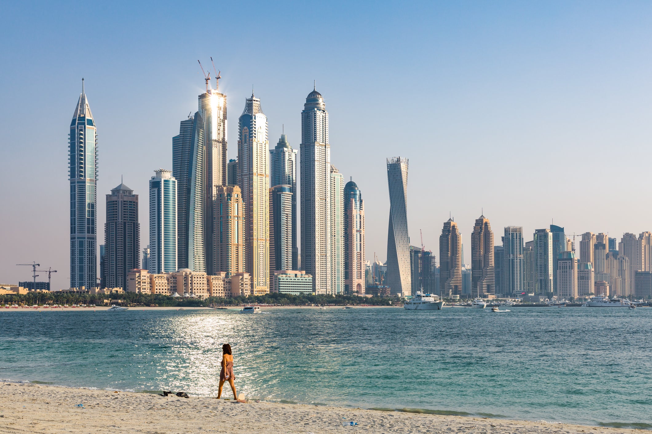Woman walking on beach in front of Dubai skyline