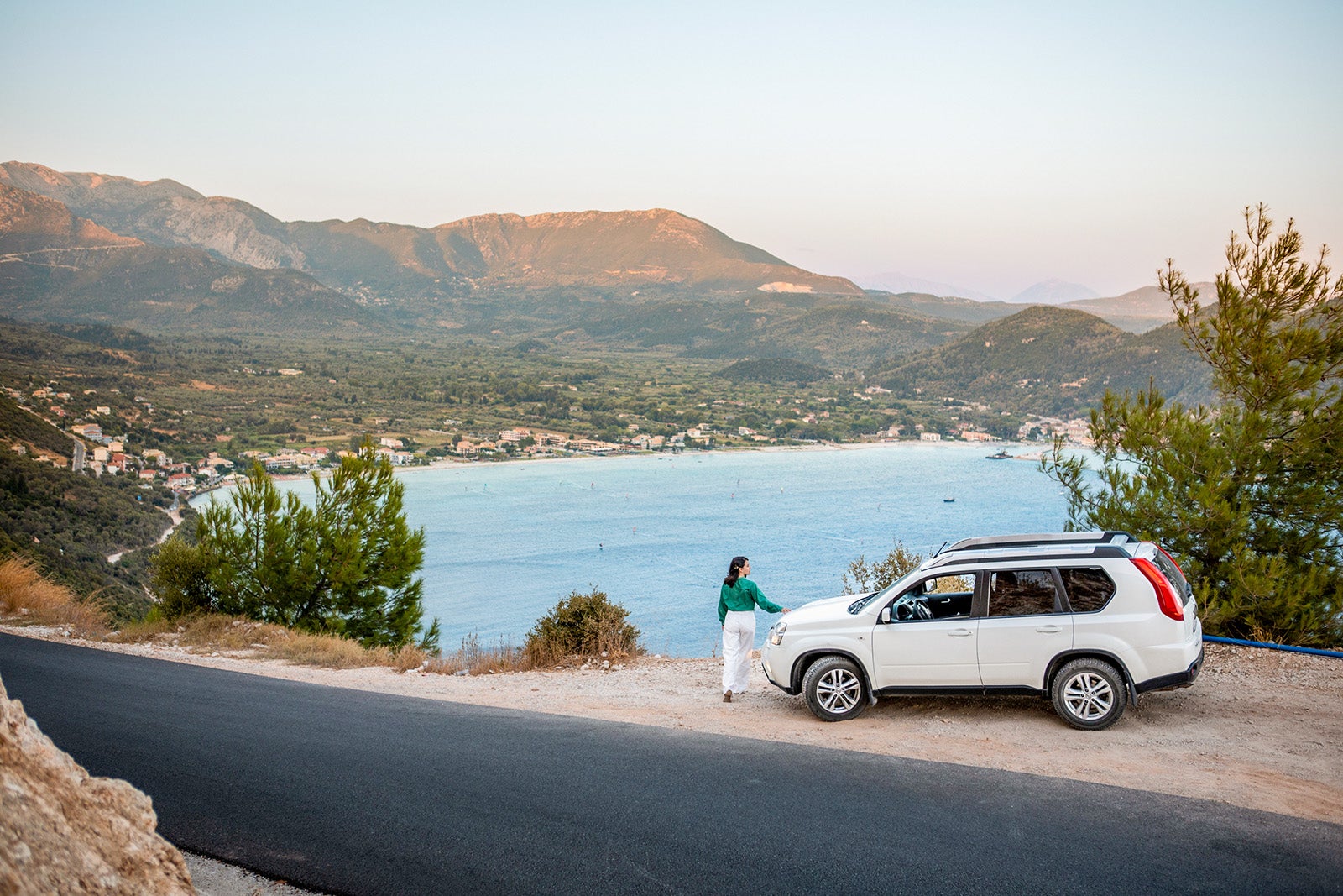 car travel concept. woman standing at the cliff looking at sea bay