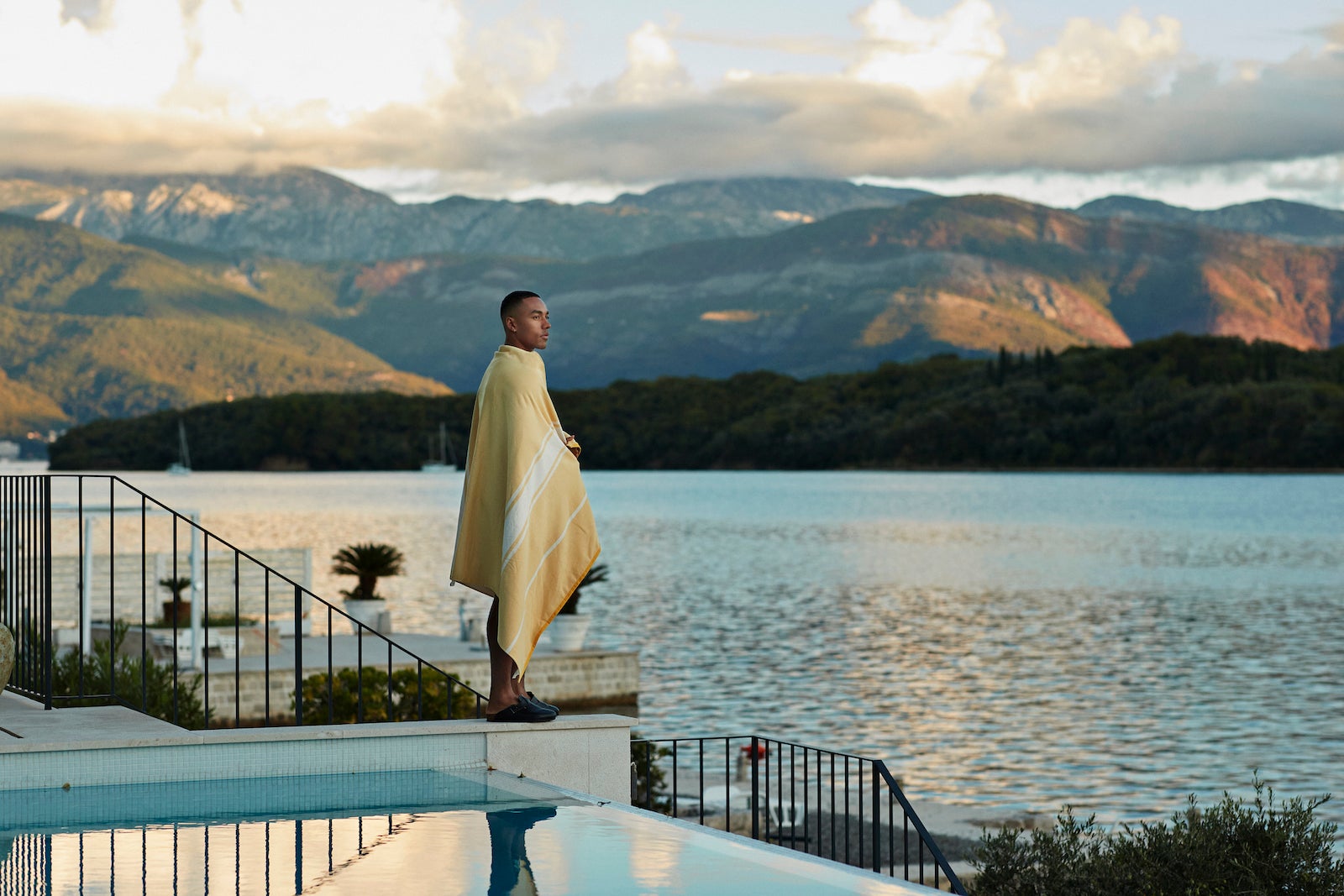 Man wrapped in blanket standing by swimming pool