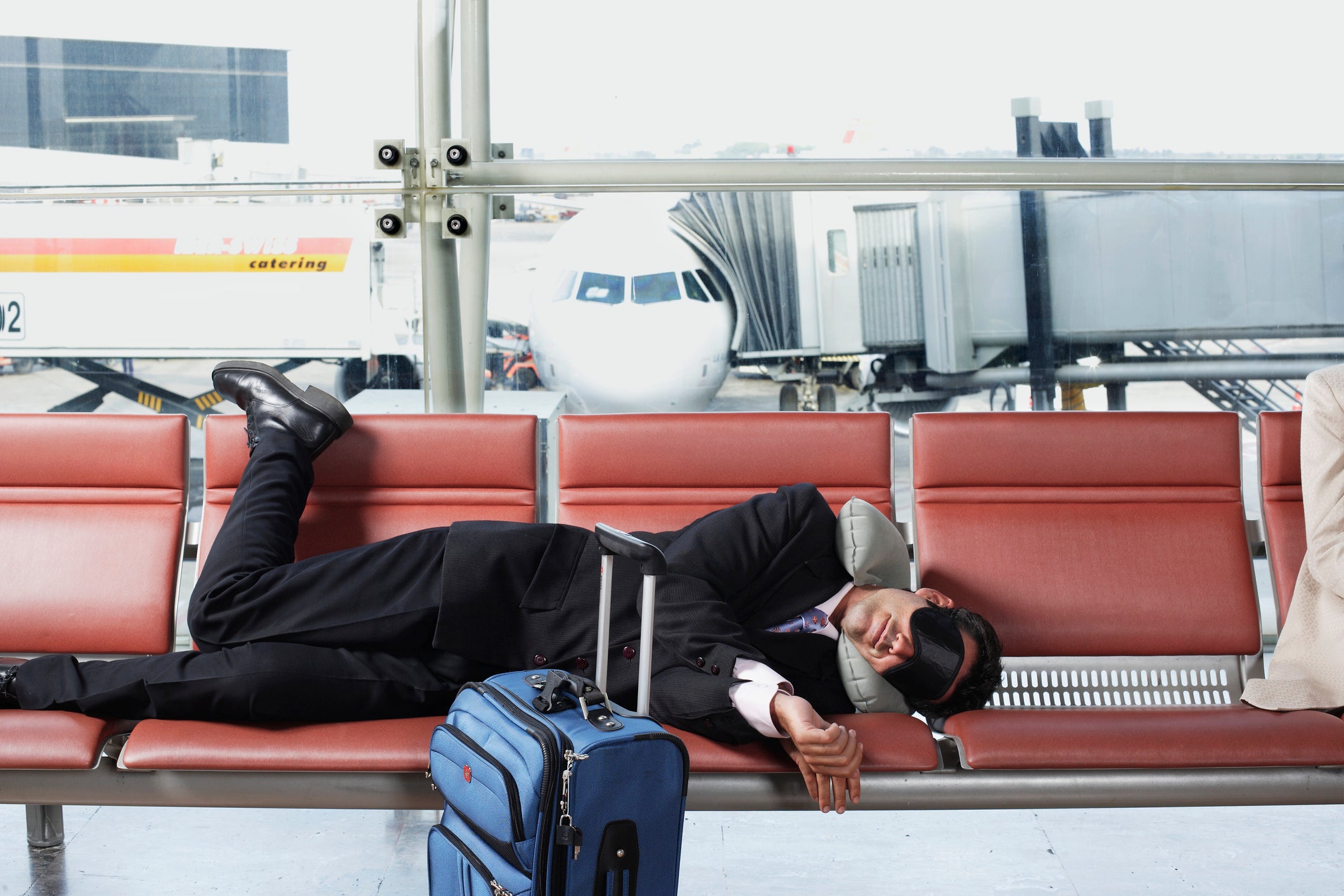 person sleeps on chairs in airport