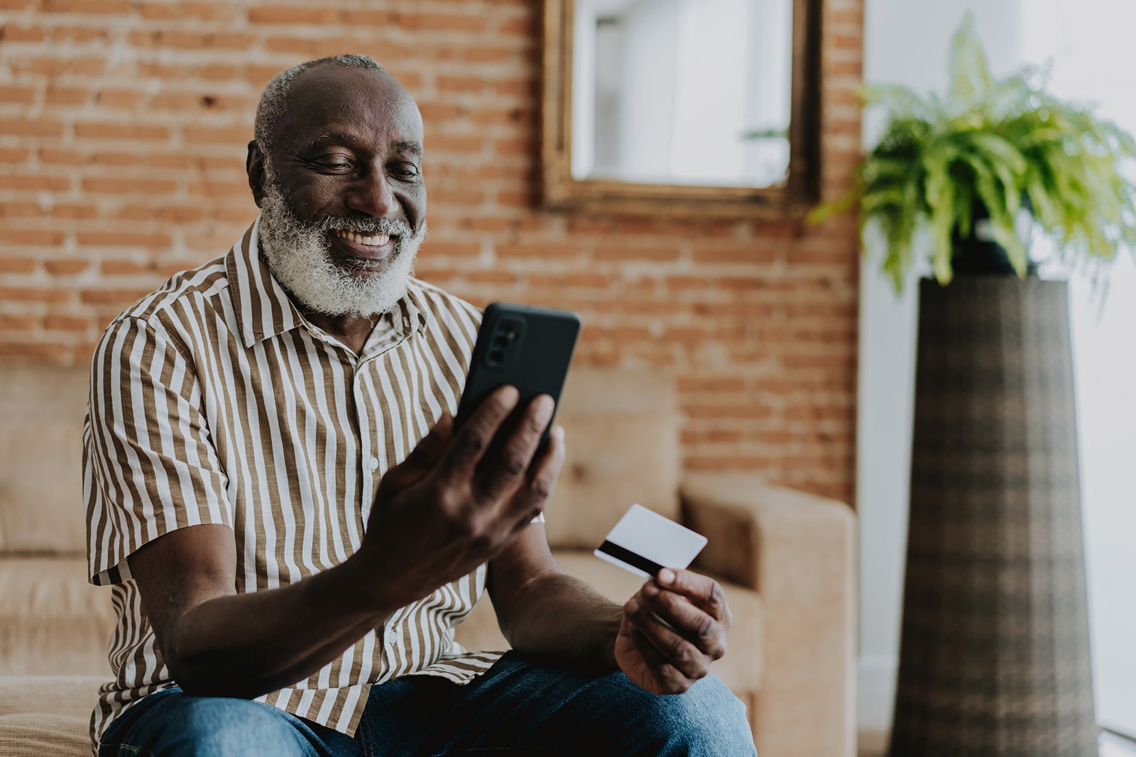 Portrait of senior man shopping by smartphone with credit card