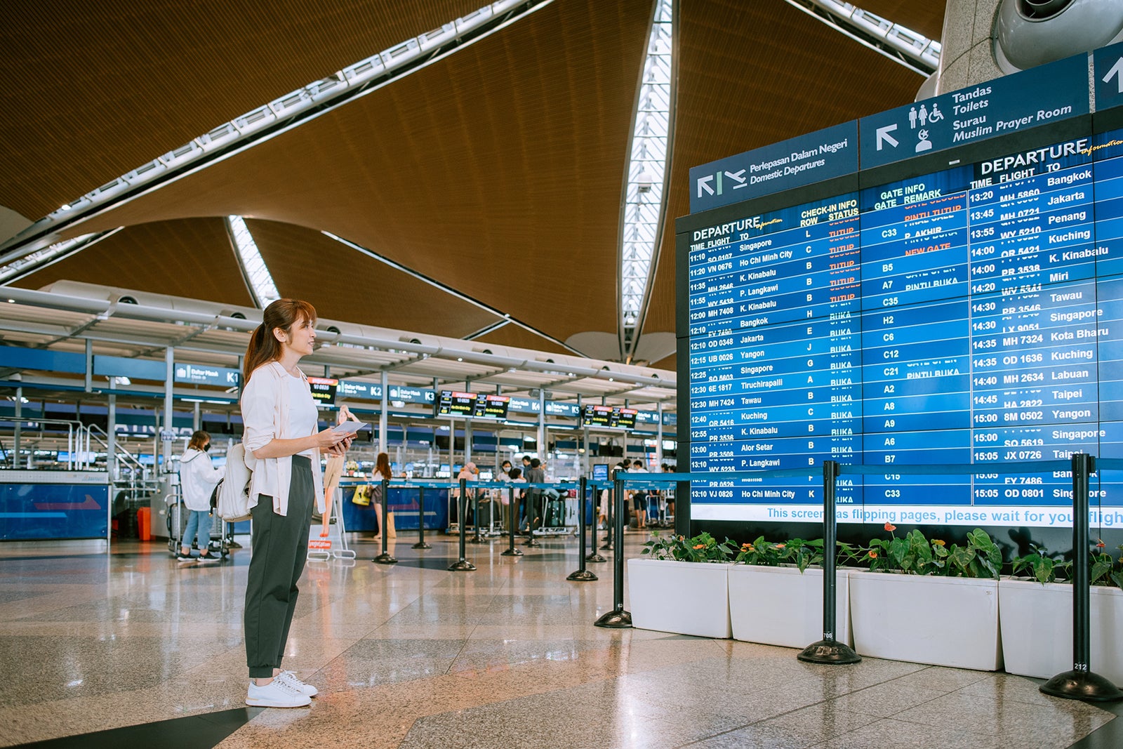 Passenger woman looking flight schedule time table at arrival departure board