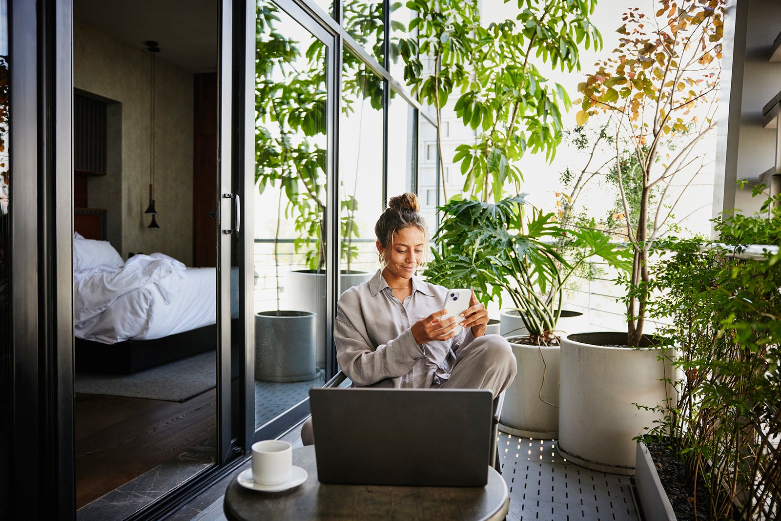 Medium wide shot woman checking smart phone on deck of hotel suite