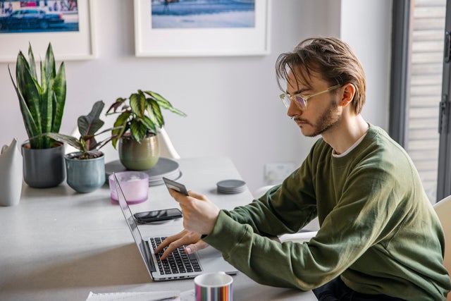Non binary person making an online purchase at home using their credit card