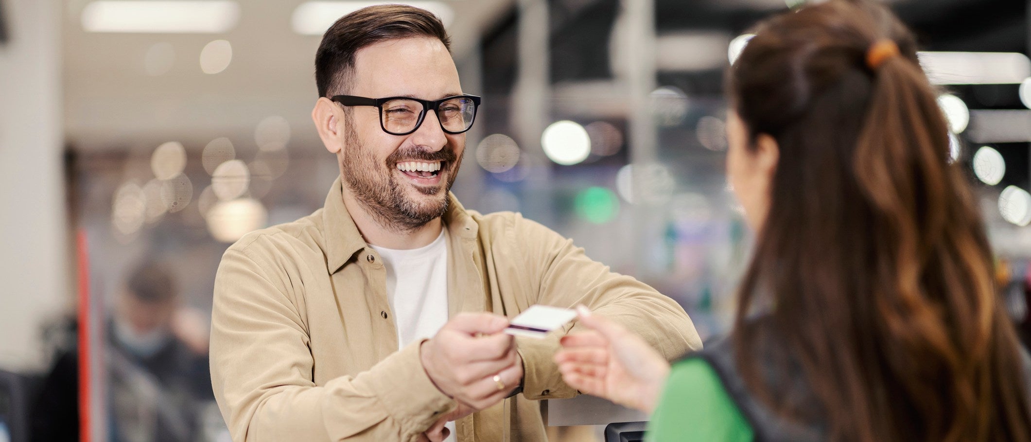 A happy man giving credit card to cashier in supermarket and paying check.