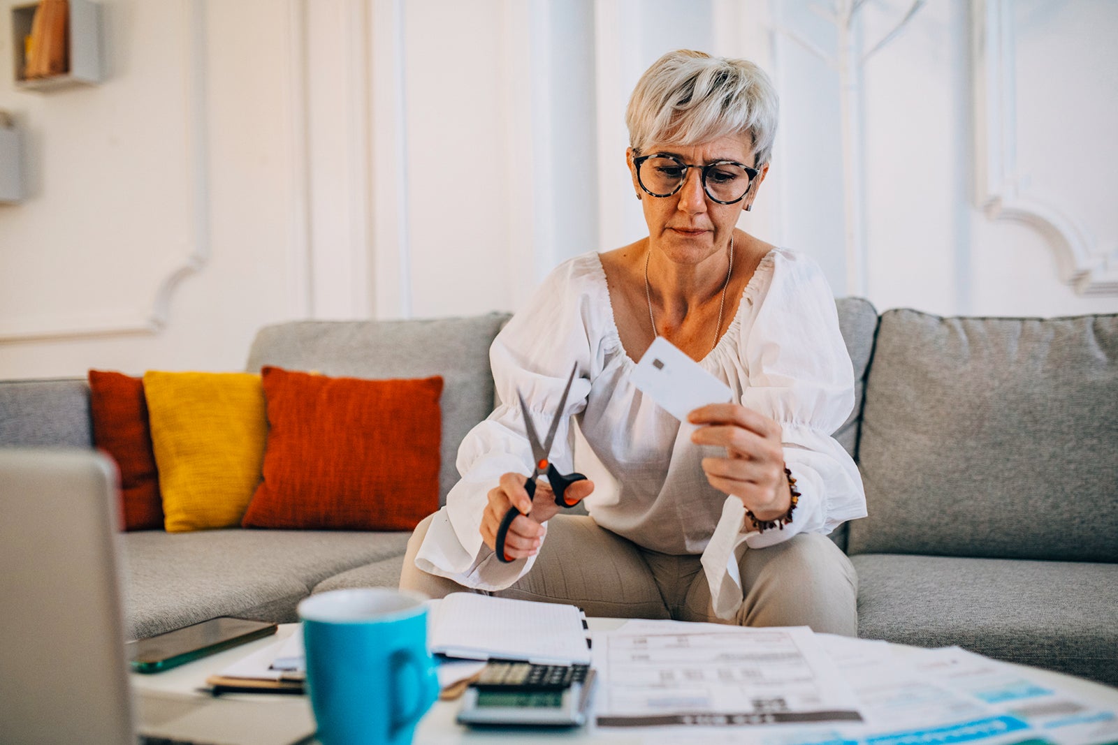 Woman cutting her credit card at home, she is in debt and can pay the bills and taxes