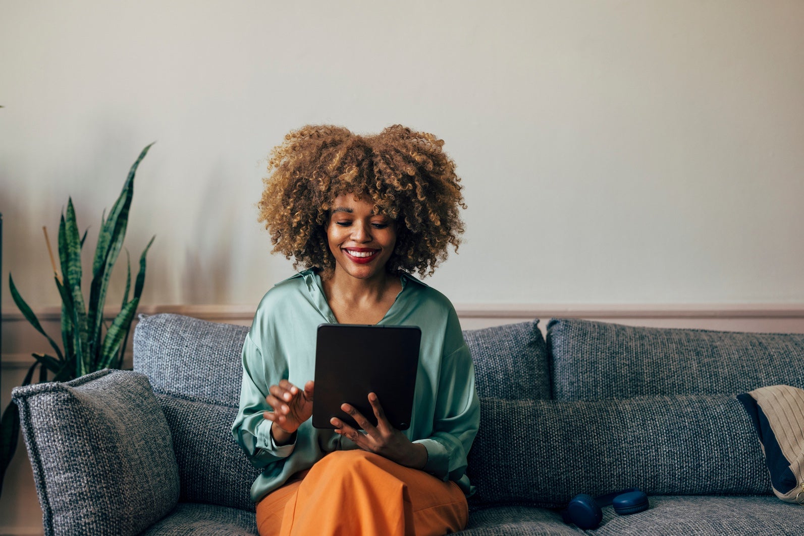 Happy African American Woman Using Tablet on a Cozy Sofa at Home