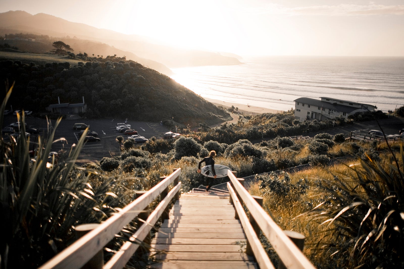 Surfer with board running down to the beach on stairs.